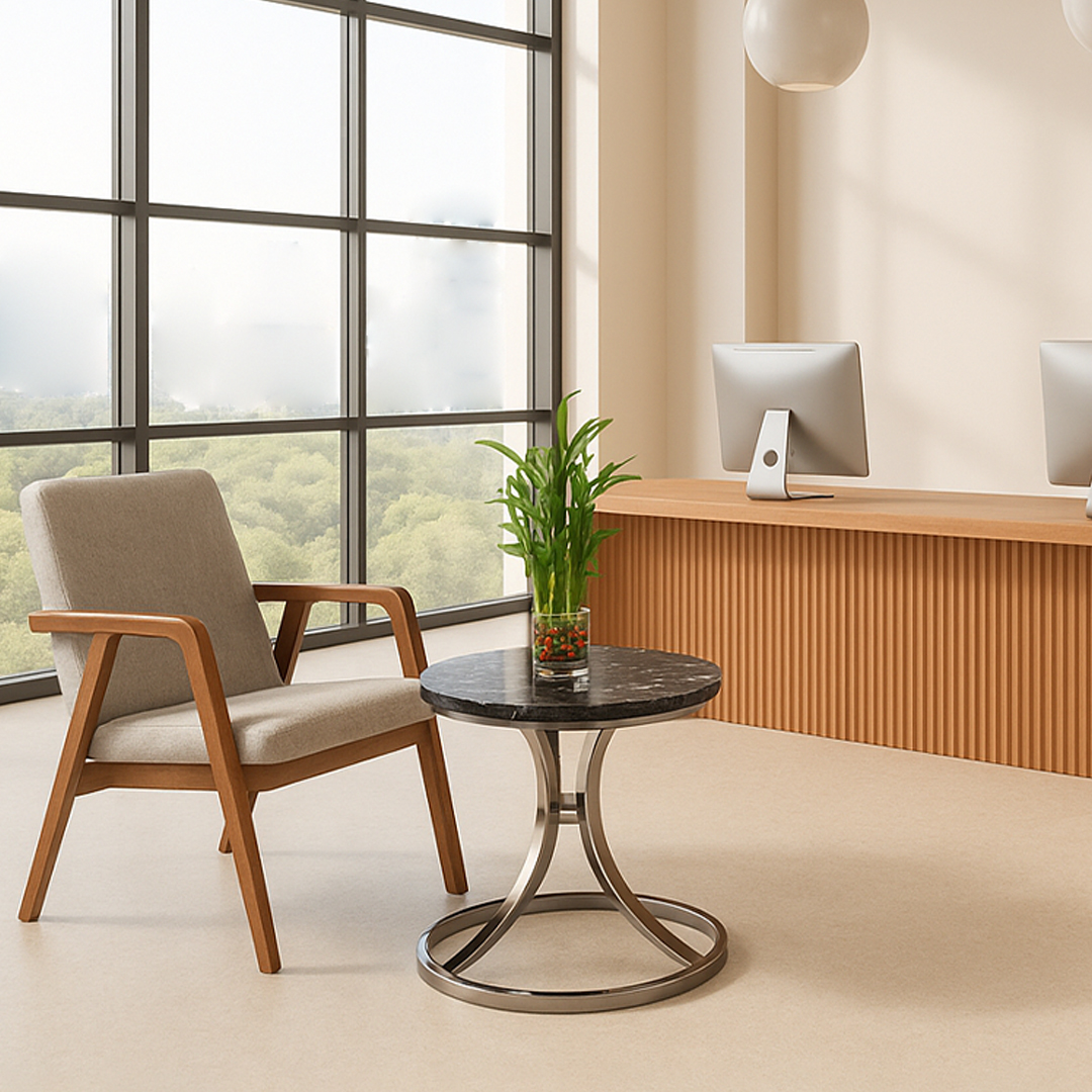 Contemporary office space with a large window view, features a cozy armchair, a round table with a green plant, and wooden reception desk with computers.