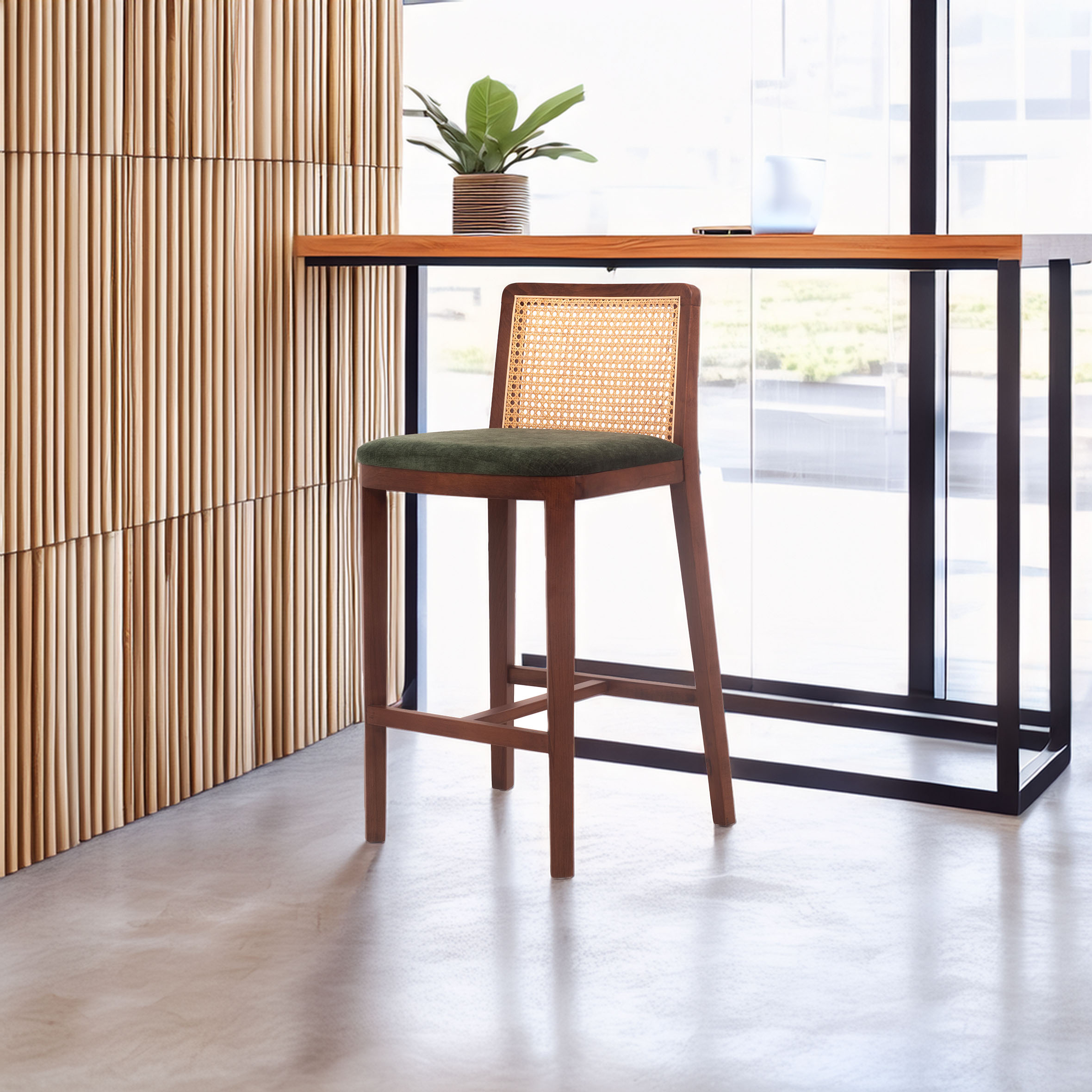 A wooden chair with a woven back and green cushion sits near a modern table. A potted plant and laptop are on the table. The setting is bright and minimalist.