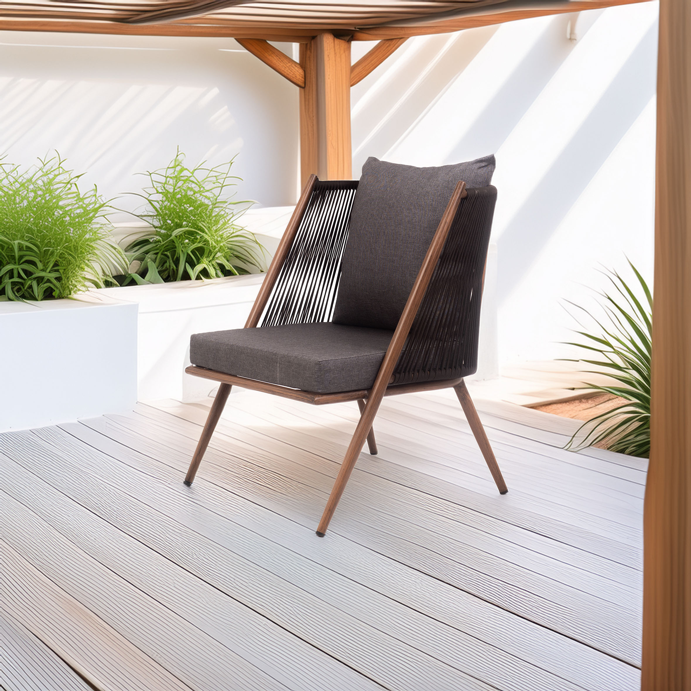 Modern lounge chair with dark cushions and wooden frame on a sunlit patio. Surrounded by lush green plants, creating a serene, stylish ambiance.