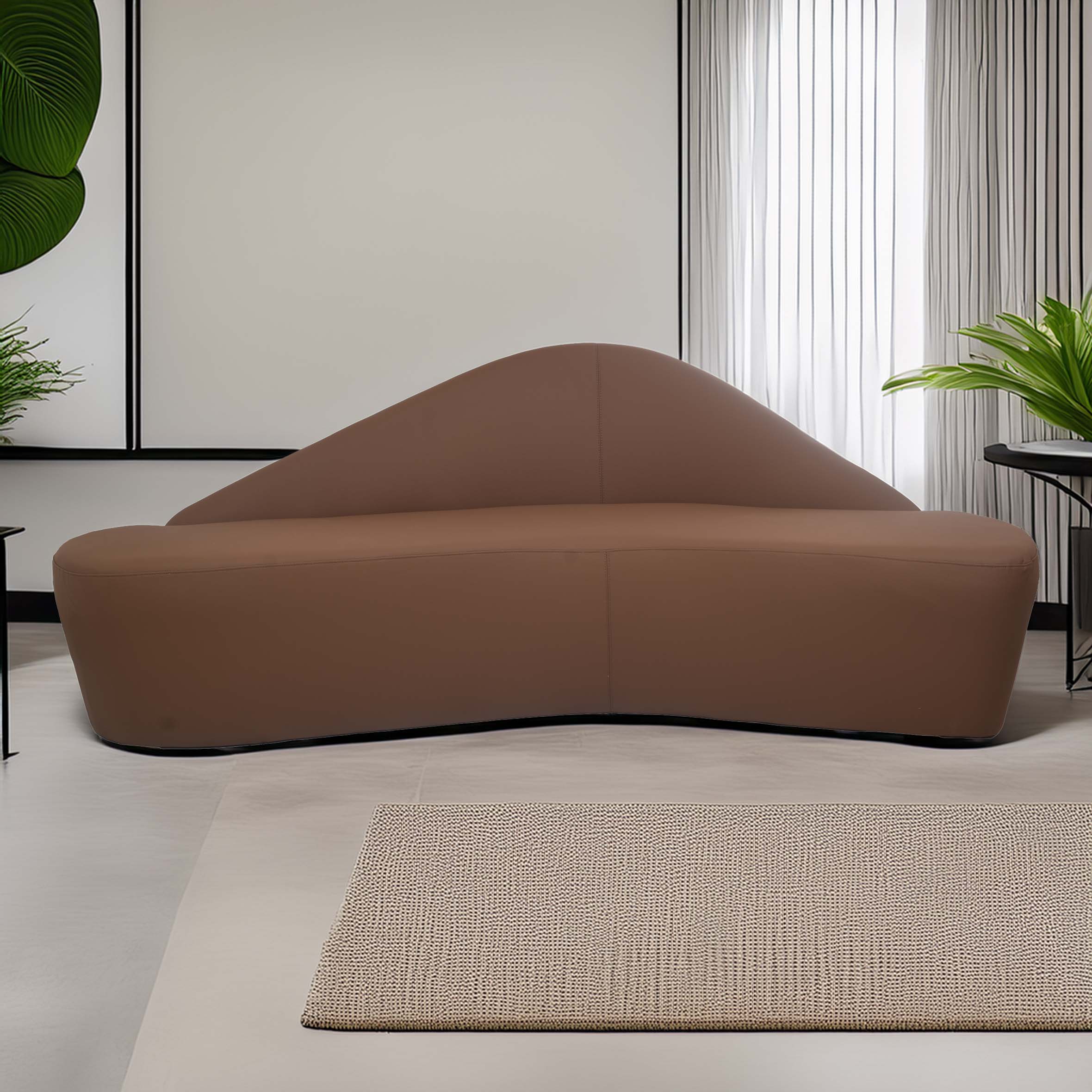 Contemporary living room with a brown, sculptural sofa, beige textured rug, and lush green plants. Light filters through sheer white curtains.