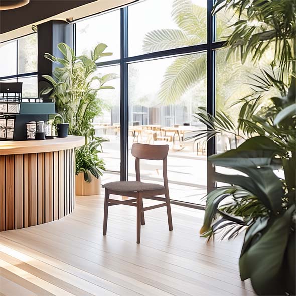 Modern cafe interior with natural light, featuring a central wooden chair. Lush green plants surround the wooden counter, creating a serene atmosphere.