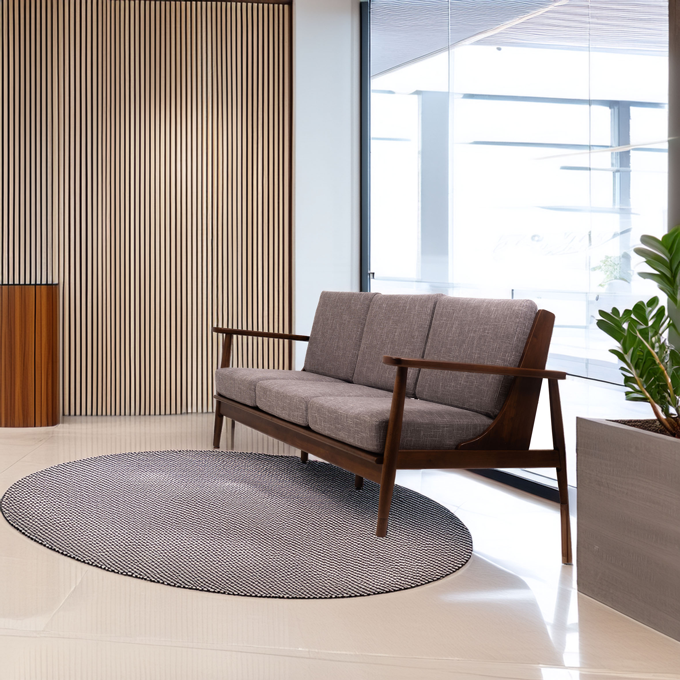 Modern lobby with a gray three-seater sofa on a circular textured rug. Wooden slatted wall and large glass window enhance the elegant space.