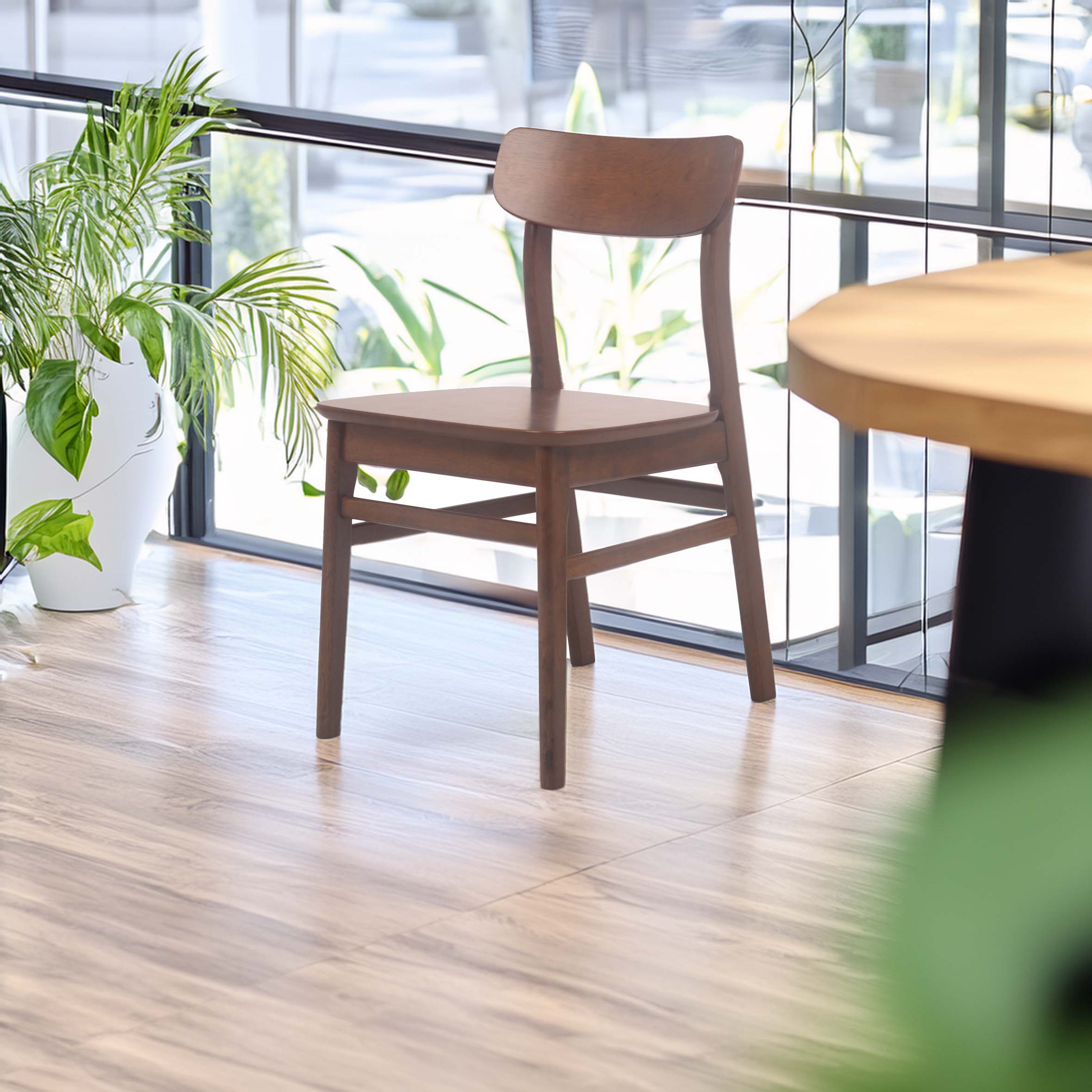 A wooden chair on a wooden floor by large windows with natural light. Potted plants add greenery, creating a calm, airy, minimalist setting.
